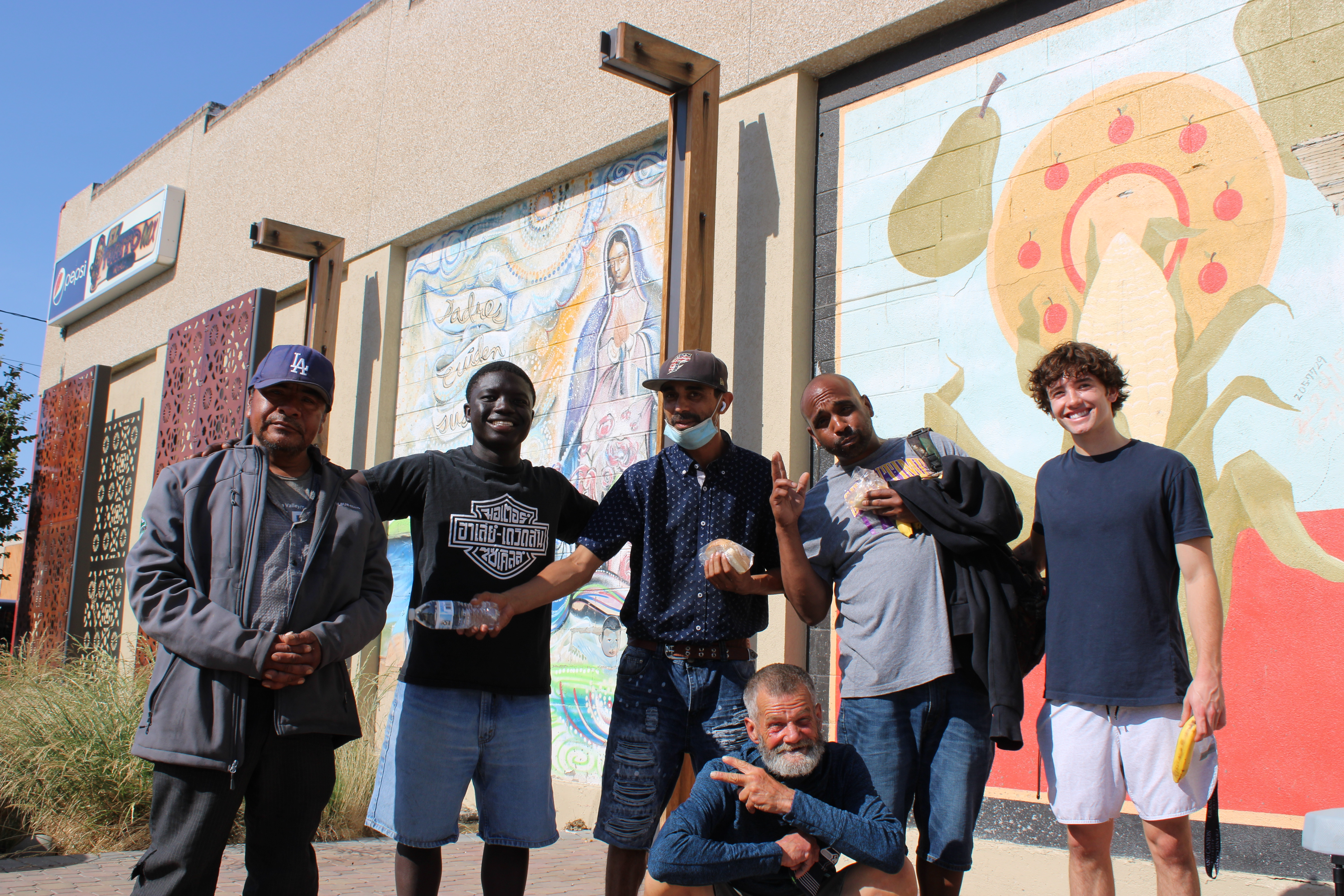 Volunteers and neighbors smiling together in front of a mural